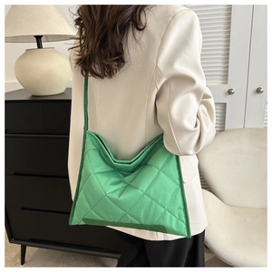 Bright green quilted crossbody bag with diamond stitching shown on model in a minimalist room