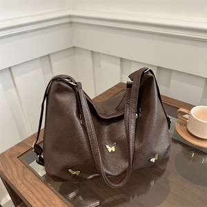 Deep brown large capacity hobo bag with gold butterfly accents in a warm setting