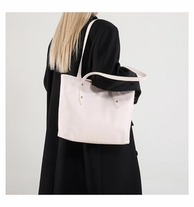 Borsa tote beige in pelle martellata indossata da modella con cappotto nero lungo