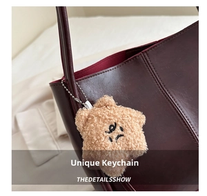 Détail d'un porte-clés en peluche en forme d'étoile sur un sac cabas en cuir bordeaux