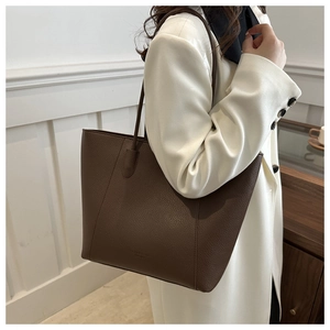Detail of dark brown lychee leather tote bag showing fine stitching and embossed logo