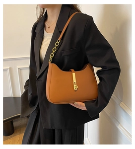 Detail der karamellbraunen Moon Bag mit goldener Metallschnalle auf schwarzem Blazer