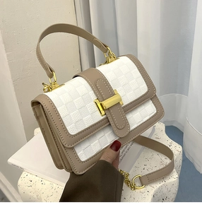 Detail of white and beige checkered crossbody bag with premium gold buckle and chain