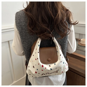 Vista posteriore del modello con borsa tote retrò bianca a pois e patta in pelle marrone