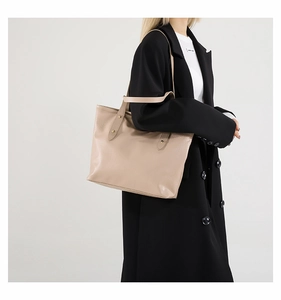 Vista laterale della borsa tote in pelle beige con rivetti in metallo e tracolla lunga