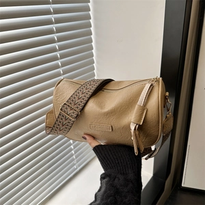 Chic beige cylinder shoulder bag with a vintage patterned wide strap and zipper closure