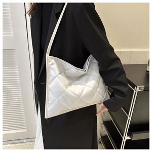 Close-up of quilted rhombus patterns on a cream Oxford tote bag shown on shoulder