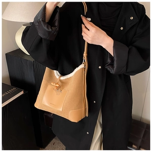 Detail of wool bucket bag featuring white faux fur trim and elegant wooden toggle closure