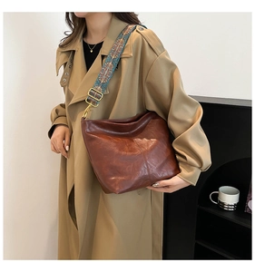 Brown bucket bag with retro textured leather and a colorful ethnic style woven strap