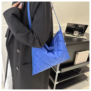 Detail view of shiny blue quilted nylon tote bag with rhombus patterns and slim strap