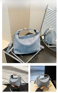 Detail of light blue textured handbag showing golden metal buckle and zipper closure
