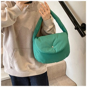 Detail of mint green quilted puffer shoulder bag with silver snap button on a casual model