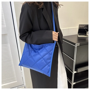 Blue quilted crossbody tote bag in nylon fabric worn with a professional office outfit