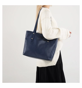 Borsa tote blu navy con stampa coccodrillo e borchie dorate indossata da modella