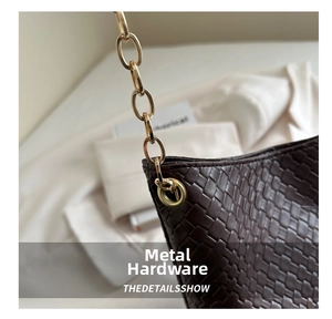 Close-up of luxury woven leather texture and gold chain metal eyelet on dark brown bag