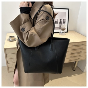 Close-up of black litchi grain leather tote bag worn with a khaki trench coat
