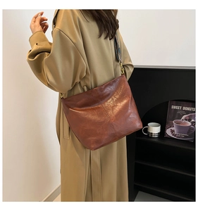 Detail of vintage brown PU leather bucket bag with a colorful ethnic woven shoulder strap