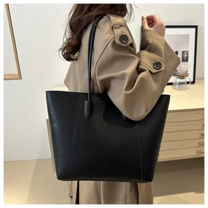 Close-up of black lychee grain leather tote bag worn by a model in a stylish interior