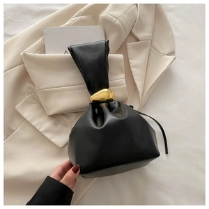 Gros plan détaillé d'un sac seau noir plissé avec une boucle dorée irrégulière en métal