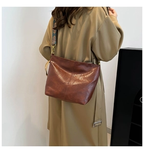 Detail of caramel brown leather bucket bag with vintage geometric patterned strap