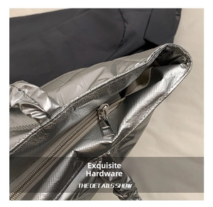 Detail of silver metallic quilted tote bag with smooth zipper closure and metal puller