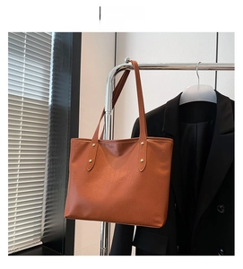 Dettaglio della borsa tote in pelle goffrata coccodrillo marrone con rivetti dorati