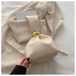 Gros plan d'un sac seau beige plissé avec une grande boucle en métal doré type galet