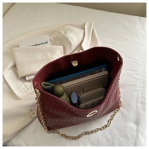 Spacious burgundy woven tote with gold chain strap, showing interior capacity and daily items