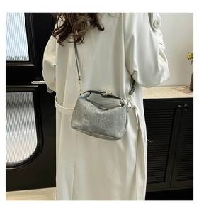 Detailed view of gray crossbody bag with vintage texture on a model in white coat