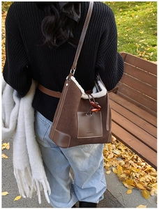 Detail view of brown corduroy tote with plush lining and leather strap in autumn setting