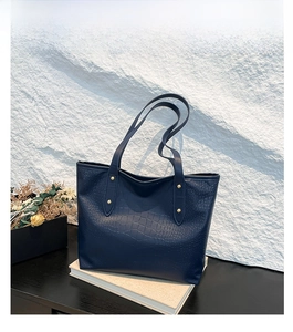 Dettaglio della borsa tote blu motivo coccodrillo con rivetti dorati e manici robusti