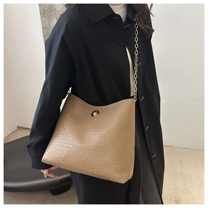 Detail of khaki embossed shoulder bag with golden chain strap and round turn-lock