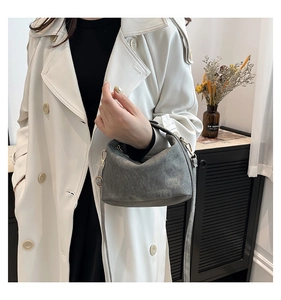 Close-up of grey vintage canvas crossbody bag with top handle worn on beige trench coat