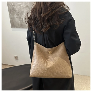 Close-up of a beige textured leather crossbody bag with a golden chain strap and swivel lock
