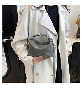 Detail of gray PU leather handbag with matte texture and metallic buckle on white coat