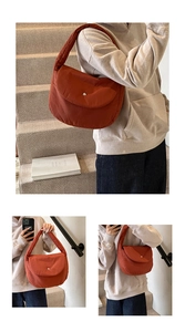 Detail of orange quilted puffer shoulder bag with silver magnetic snap button closure
