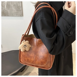 Detail of vintage brown textured leather tote bag with a cute plush star bag charm