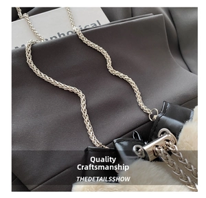 Detail of plush bucket bag with golden woven chain strap and black pebbled leather