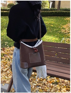 Close-up of brown suede shoulder bag with white faux fur trim and drawstring detail