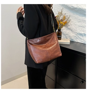 Detailed view of brown leather bucket bag with a colorful ethnic style woven shoulder strap