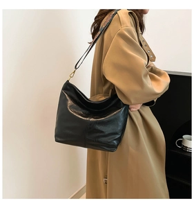 Detail of a large black shoulder bag with a vintage colorful woven wide strap and metal clip