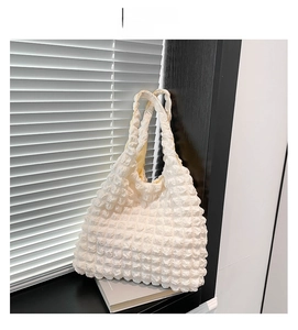 Close-up of white bubble pleated fabric texture and dual handles on a minimalist tote bag