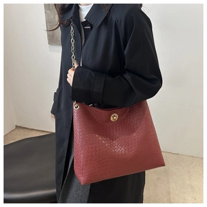 Macro detail of wine red woven leather bag with round gold metal lock and chain