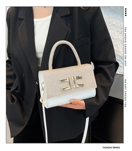 Detail of the glittering sequins and the gold EE metal buckle on the white square handbag