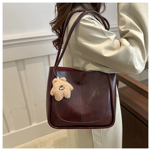 Detail of dark red tote bag with U-shaped stitching and cute star plush pendant