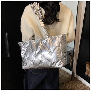 Detail of silver quilted tote bag with metallic finish and ruffled shoulder strap