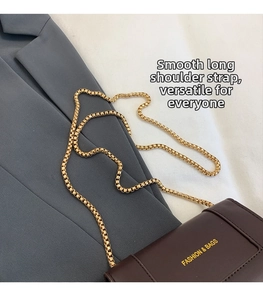 Detail of dark brown leather crossbody bag featuring a golden chain strap and logo