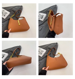 Detail view of brown leather crescent bag showing gold metal clasp and chain strap