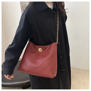 Close-up of wine red crocodile pattern leather bag with gold chain and round twist lock