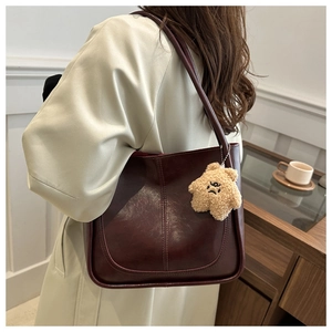Détail d'un sac cabas en cuir bordeaux avec pendentif étoile en peluche porté par un mannequin